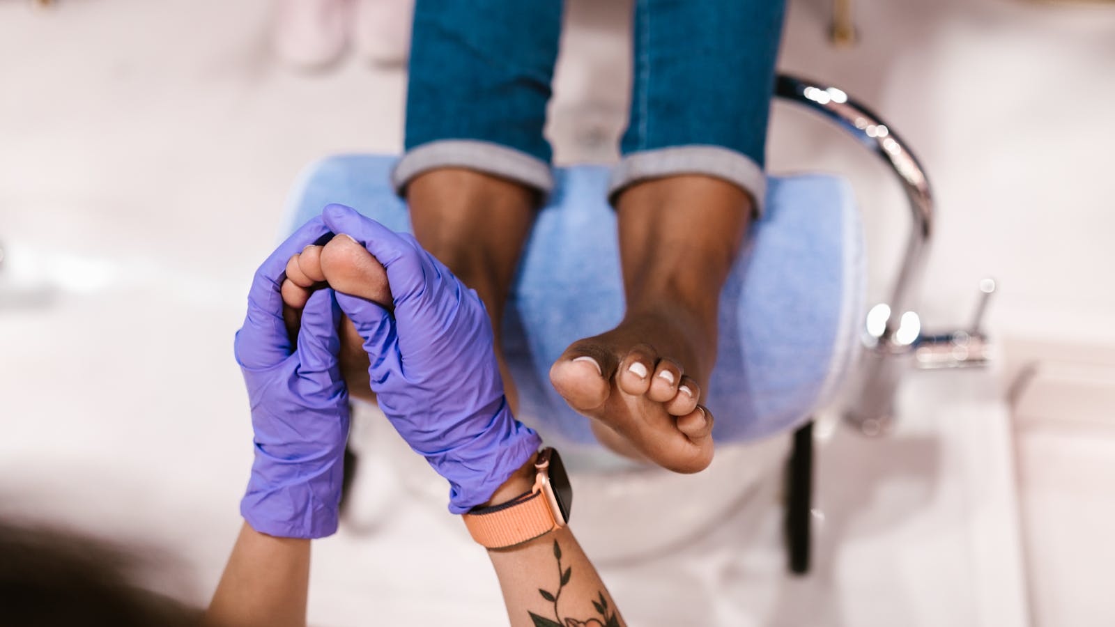 Gloved hands inspecting a client's toes during a professional foot care appointment.
