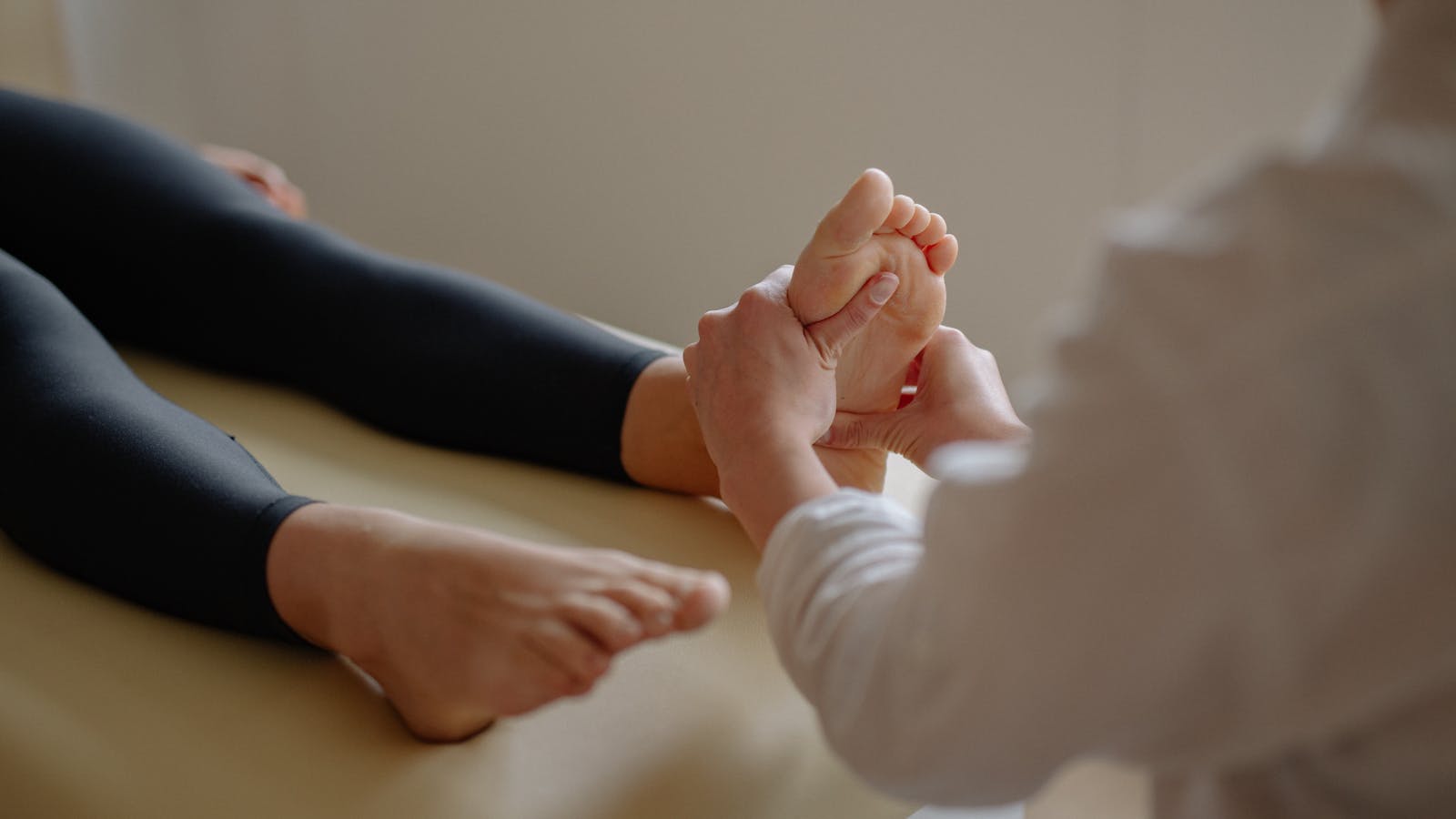 Foot care provider gently holding and examining a client's bare foot during a professional care visit.